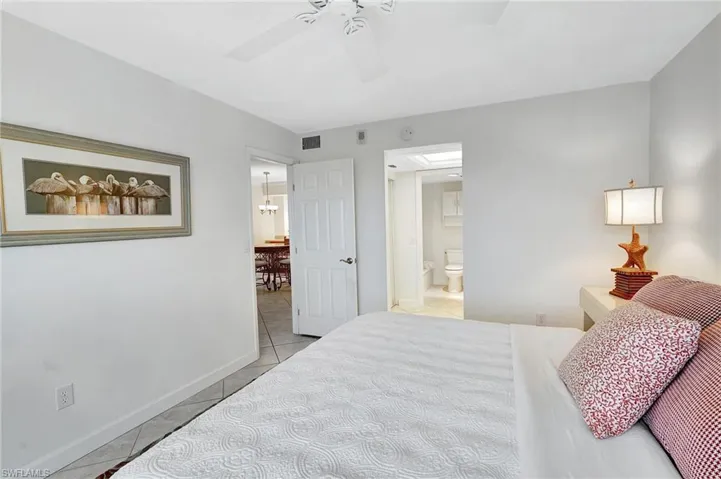 Bedroom featuring light tile patterned floors, a ceiling fan, connected bathroom, and a chandelier