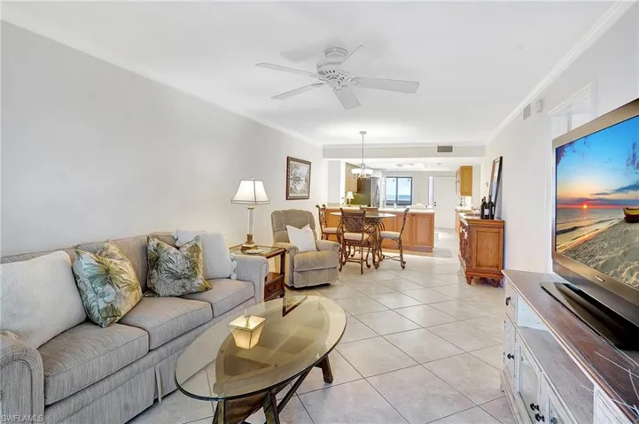 Living area featuring crown molding, light tile patterned flooring, and ceiling fan