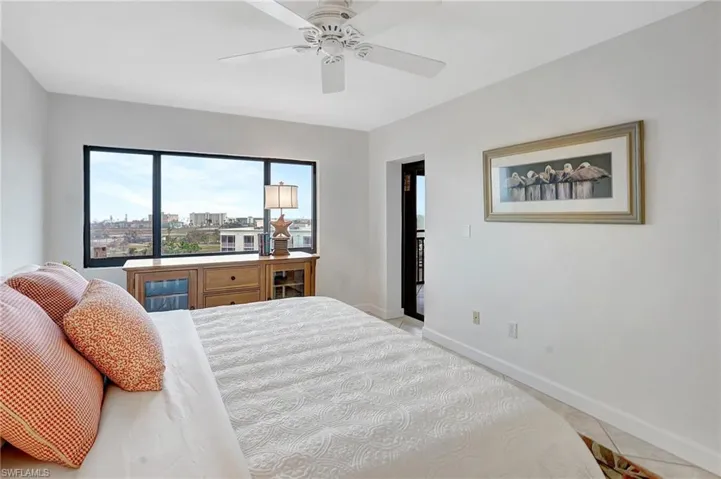 Bedroom with light tile patterned floors, a city view, and a ceiling fan