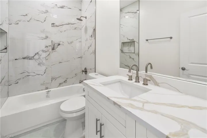 Bathroom with vanity, shower / bathtub combination, and marble finish flooring