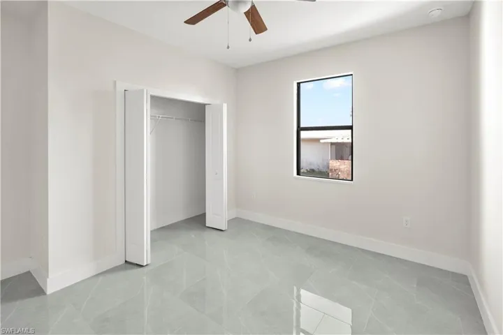 Unfurnished bedroom with ceiling fan and a closet