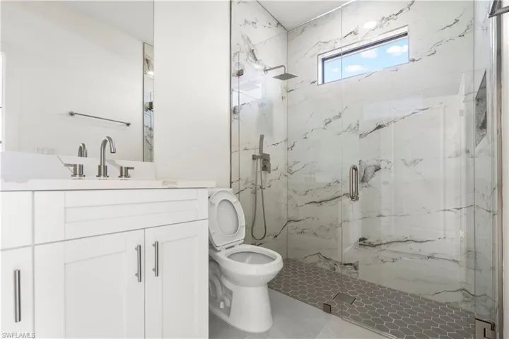 Bathroom featuring a marble finish shower and vanity