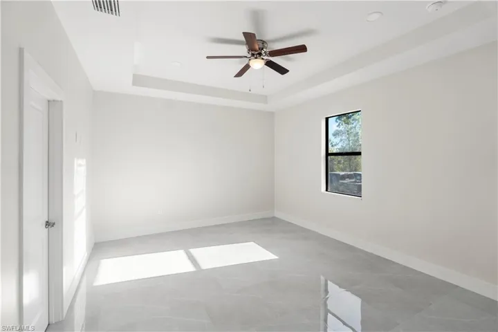 Empty room with ceiling fan and a raised ceiling