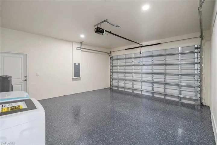 Garage with washer / clothes dryer, water heater, electric panel, and a garage door opener