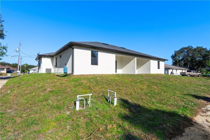 View of side of property with lawncare items, a yard, and stucco siding