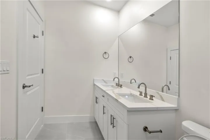 Bathroom with double vanity and light tile patterned floors