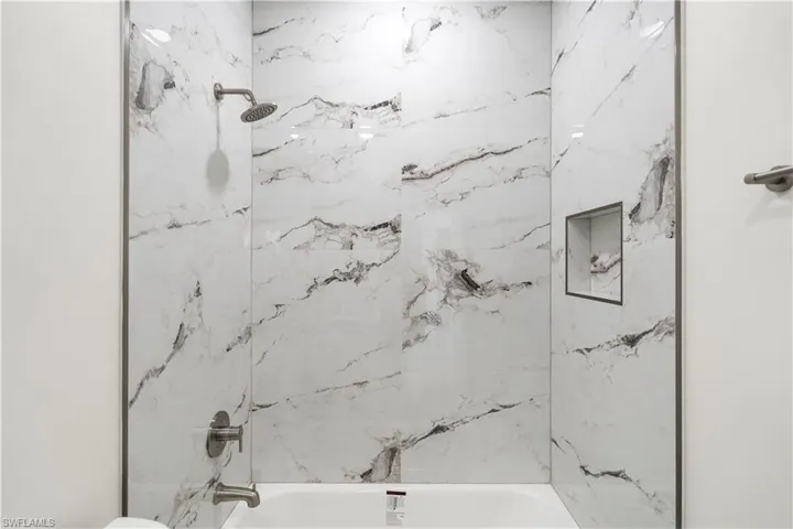 Bathroom featuring a combined bath / shower with marble appearance and toilet