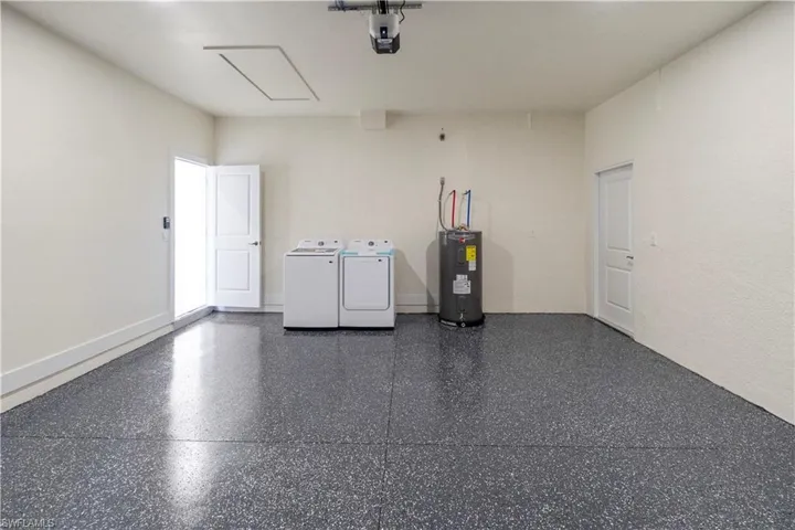 Garage featuring separate washer and dryer, water heater, and a garage door opener