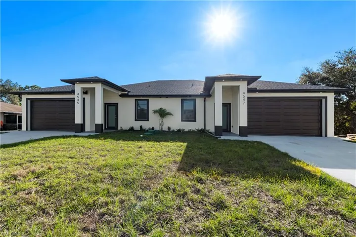 Prairie-style house with an attached garage, a front lawn, driveway, and stucco siding