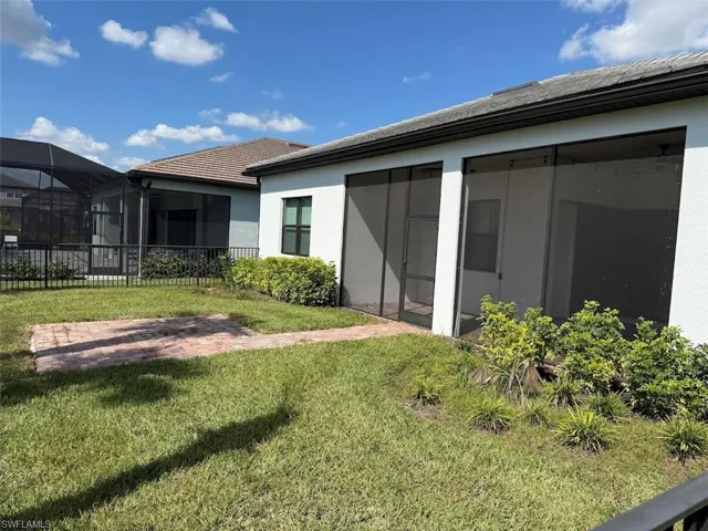 Rear view of house with a screened porch, stucco siding, and a lanai