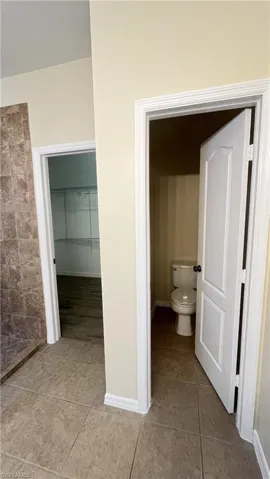 Bathroom with a walk in closet and light tile patterned floors