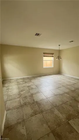 Spare room with baseboards and a chandelier