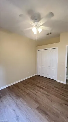 Unfurnished bedroom featuring a closet, dark wood finished floors, and a ceiling fan