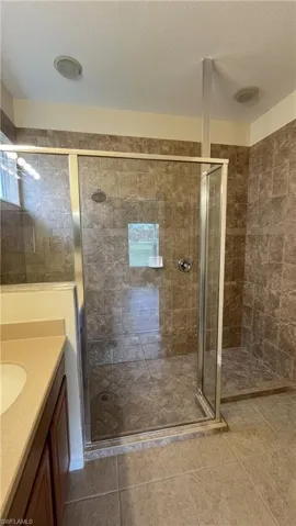 Bathroom with vanity, a textured ceiling, a shower stall, and light tile patterned floors