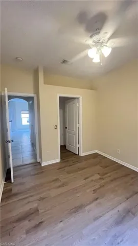 Unfurnished bedroom with wood finished floors, ceiling fan, a textured ceiling, and arched walkways