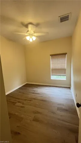 Empty room with a textured ceiling, wood finished floors, and ceiling fan