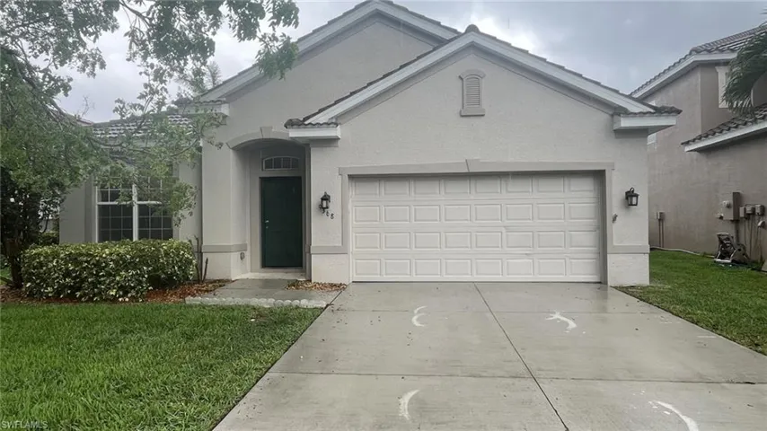 View of front of property featuring a front yard, stucco siding, driveway, and a garage
