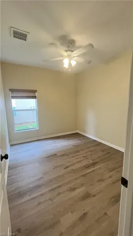 Spare room with light wood finished floors, ceiling fan, and a textured ceiling
