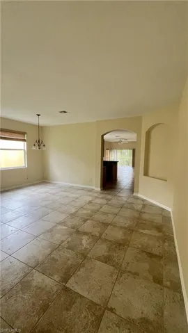 Empty room with arched walkways, a ceiling fan, and a textured ceiling