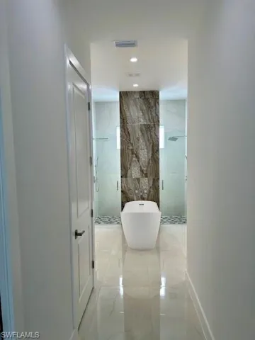 Hallway featuring tile walls and light tile patterned floors