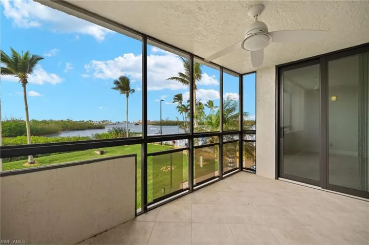 Unfurnished sunroom featuring ceiling fan, a water view, and plenty of natural light
