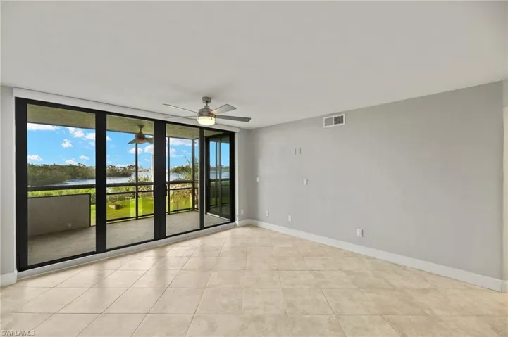 Unfurnished room featuring ceiling fan, light tile patterned flooring, and a wall of windows