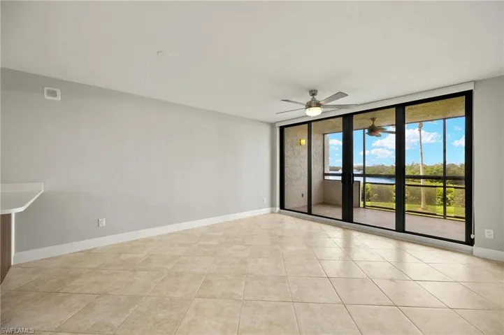 Unfurnished room featuring floor to ceiling windows, ceiling fan, and light tile patterned floors