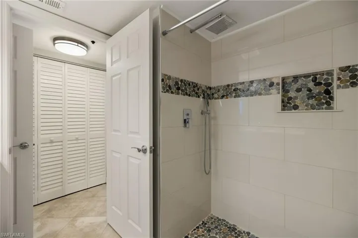 Bathroom with tiled shower and tile patterned floors