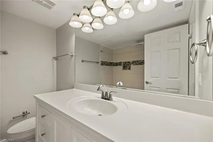 Bathroom with vanity, tiled shower, and toilet