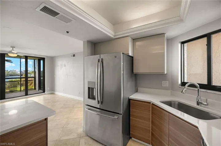 Kitchen featuring light tile patterned flooring, sink, and stainless steel fridge with ice dispenser