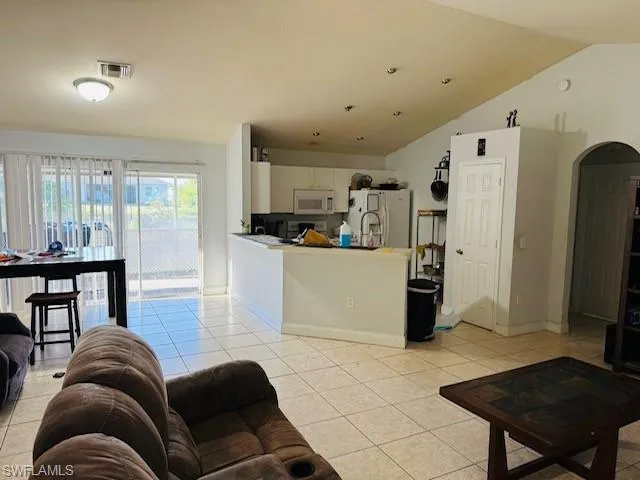 Living room with light tile patterned flooring, arched walkways, lofted ceiling, and baseboards