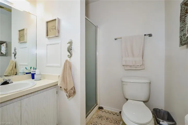 Full bath with toilet, vanity, a shower stall, and baseboards