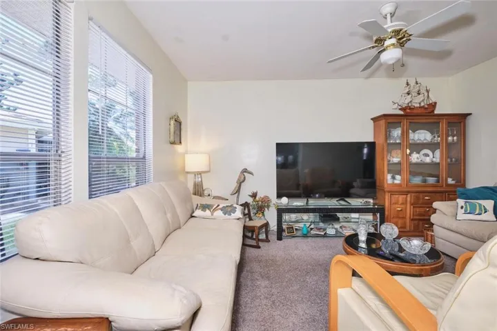 Living room featuring carpet and a ceiling fan