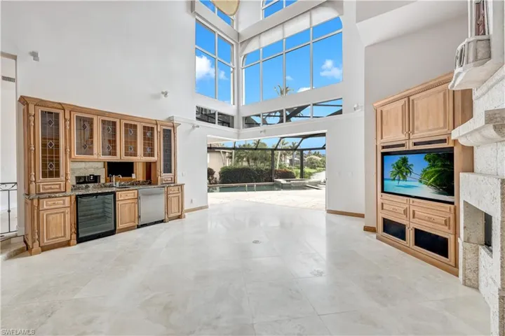 Living room featuring beverage cooler, a towering ceiling, and light marbled patterned floors.