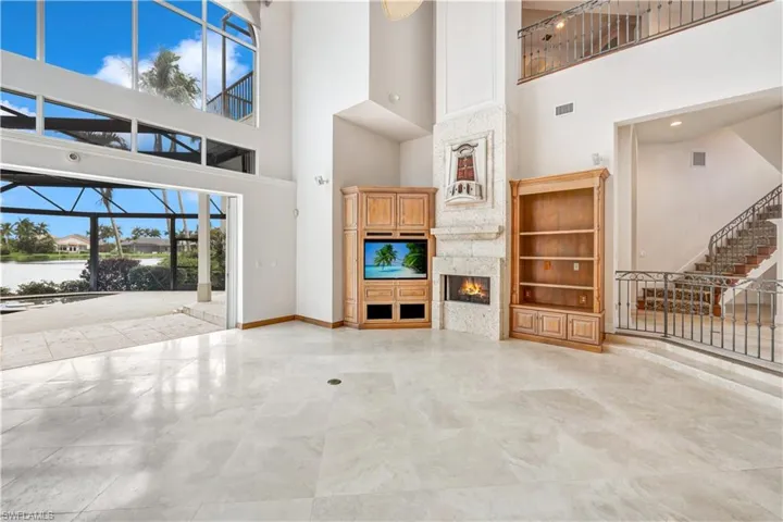 Unfurnished living room with a fireplace, a towering ceiling, built in features, and light tile patterned floors
