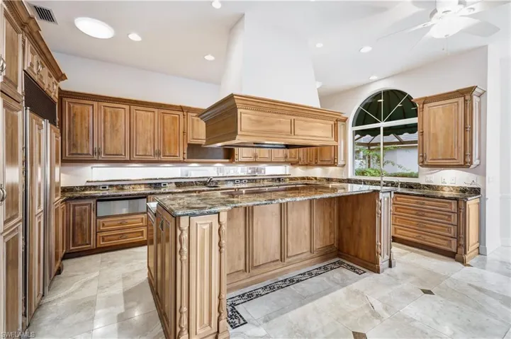 Kitchen featuring marble countertops, 2 ovens, 2 dishwashers, 2 sinks a massive island, and custom range hood.