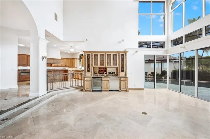 Unfurnished living room with a high ceiling, beverage cooler, ceiling fan, and light tile patterned floors