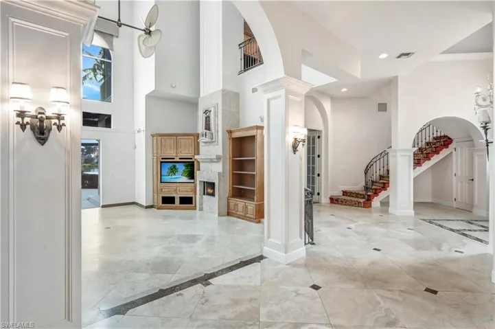 Tiled entryway with ornamental molding, ornate columns, exquisite archways, a fireplace, and towering 32 ft. ceilings in the main living area!