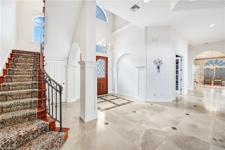 Foyer entrance featuring 24 x 24 marble patterned floors, a notable chandelier, and a towering ceilings.