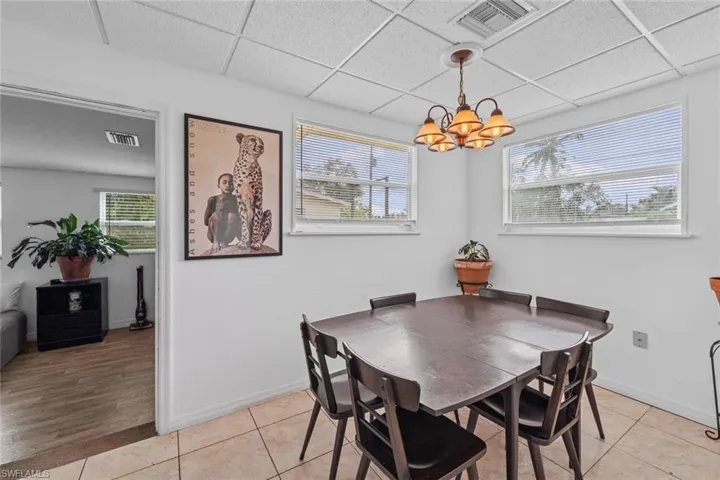 Dining space with light tile patterned flooring, a wealth of natural light, and an inviting chandelier