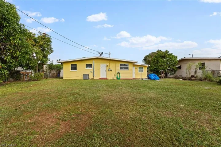 Rear view of house with a lawn and central AC unit