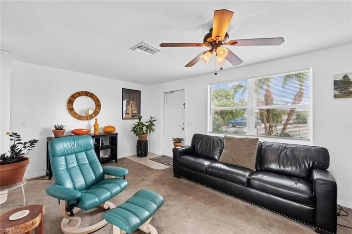 Living room featuring ceiling fan, light colored carpet, and a textured ceiling
