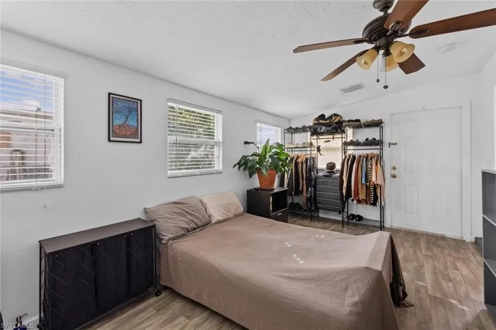 Room with hardwood / wood-style flooring, ceiling fan, lofted ceiling, and a textured ceiling