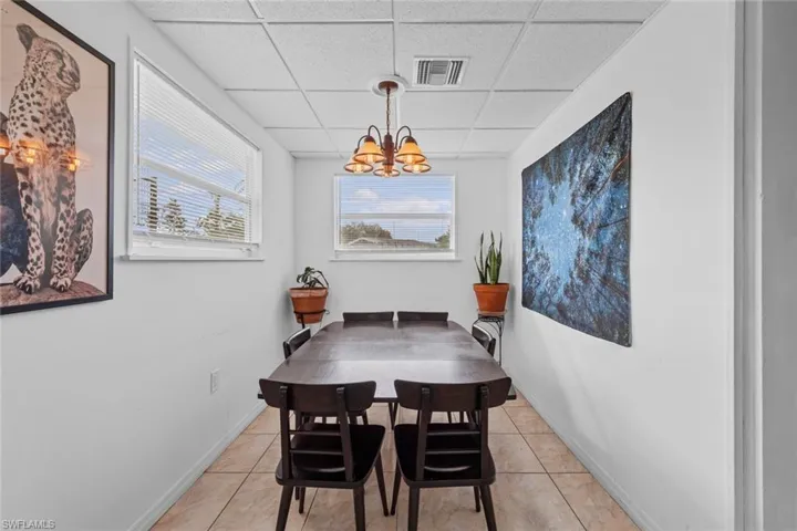 Dining area featuring a paneled ceiling, light tile patterned flooring, and an inviting chandelier