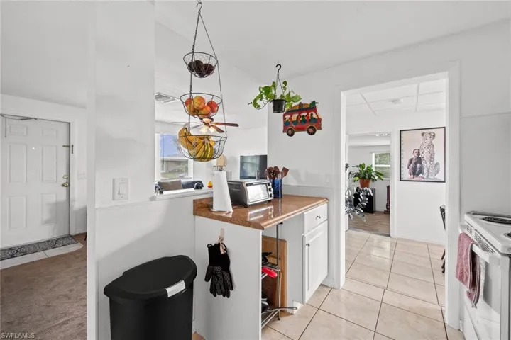 Kitchen featuring light tile patterned floors, white cabinetry, and white electric stove