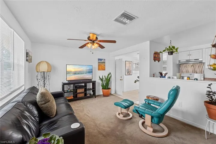 Living room with light carpet, a textured ceiling, and ceiling fan