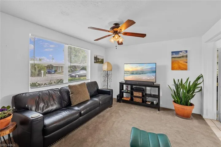 Carpeted living room with a textured ceiling and ceiling fan
