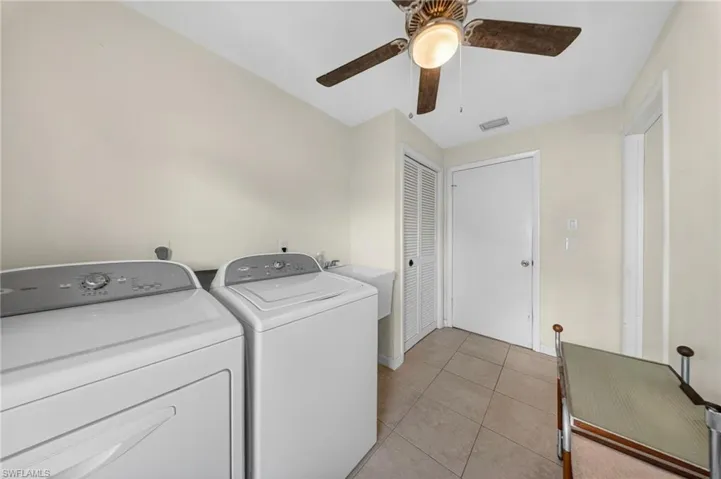 Laundry area with light tile patterned floors, washer and dryer, and a ceiling fan