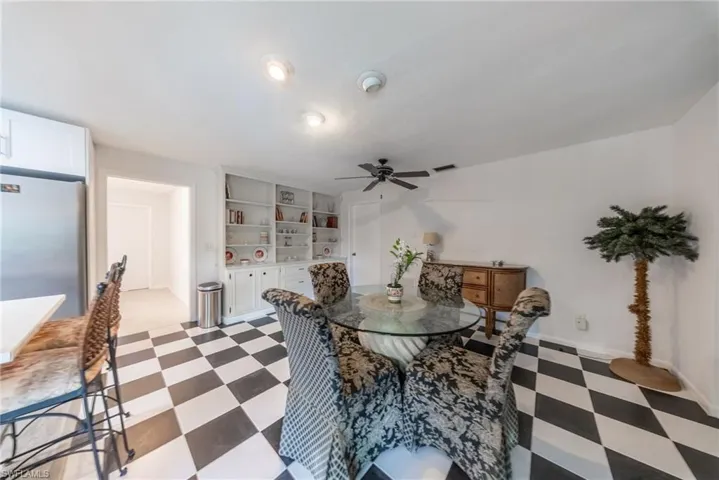 Dining space featuring dark flooring, built in shelves, and ceiling fan