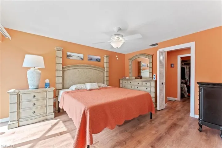 Bedroom with a ceiling fan, a spacious closet, light wood-style flooring, baseboards, and visible vents